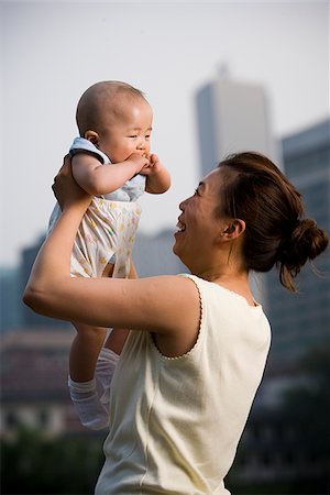Woman lifting baby outdoors and smiling Stock Photo - Premium Royalty-Free, Code: 640-02775728
