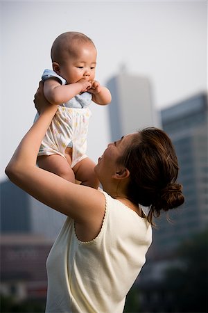 Woman lifting baby outdoors and smiling Stock Photo - Premium Royalty-Free, Code: 640-02775729