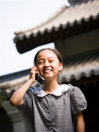 simsearch:640-02775683,k - Jeune fille debout à l'extérieur avec le téléphone cellulaire en face de la pagode souriant Photographie de stock - Premium Libres de Droits, Code: 640-02775722