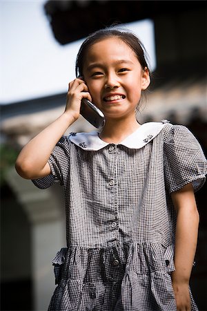 simsearch:640-02775683,k - Jeune fille debout à l'extérieur avec le téléphone cellulaire en face de la pagode souriant Photographie de stock - Premium Libres de Droits, Code: 640-02775723