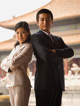 Businessman and woman standing with arms crossed and backs together with pagoda in background Stock Photo - Premium Royalty-Free, Code: 640-02775791