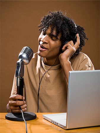 simsearch:640-02776882,k - junger Mann in ein braunes Hemd auf einem Laptop mit Kopfhörer und Mikrofon. Stockbilder - Premium RF Lizenzfrei, Bildnummer: 640-02776894