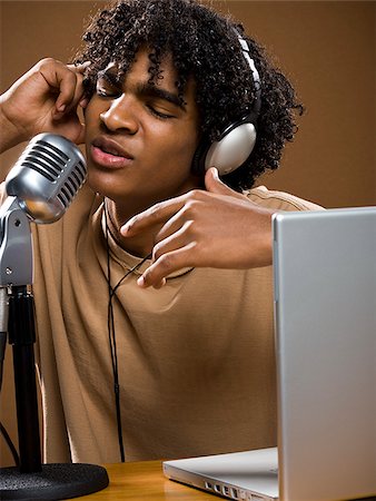 simsearch:640-02777685,k - jeune homme dans une chemise marron sur un ordinateur portable avec des écouteurs et un microphone. Photographie de stock - Premium Libres de Droits, Code: 640-02776895