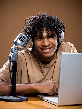simsearch:640-02777685,k - jeune homme dans une chemise marron sur un ordinateur portable avec des écouteurs et un microphone. Photographie de stock - Premium Libres de Droits, Code: 640-02776896