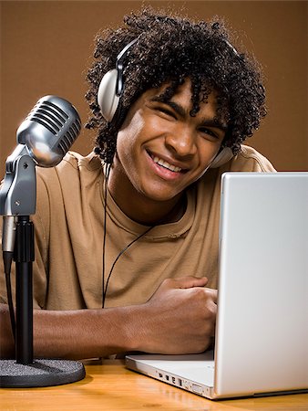simsearch:640-02776882,k - junger Mann in ein braunes Hemd auf einem Laptop mit Kopfhörer und Mikrofon. Stockbilder - Premium RF Lizenzfrei, Bildnummer: 640-02776897