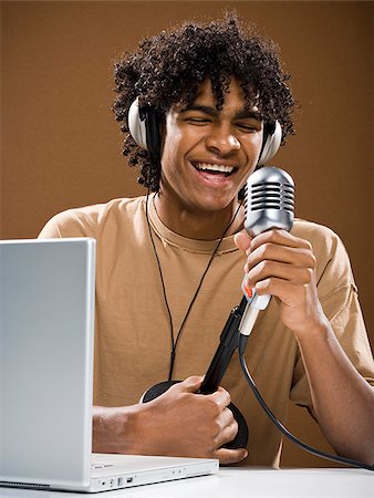 simsearch:640-02777685,k - jeune homme dans une chemise marron sur un ordinateur portable avec des écouteurs et un microphone. Photographie de stock - Premium Libres de Droits, Code: 640-02776891