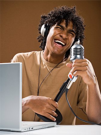 simsearch:640-02776882,k - junger Mann in ein braunes Hemd auf einem Laptop mit Kopfhörer und Mikrofon. Stockbilder - Premium RF Lizenzfrei, Bildnummer: 640-02776892