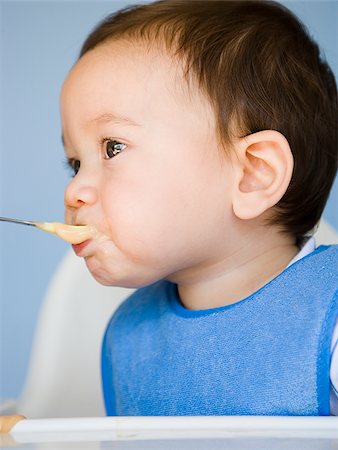 spoon feeding - baby boy with a blue bib. Stock Photo - Premium Royalty-Free, Code: 640-02777277