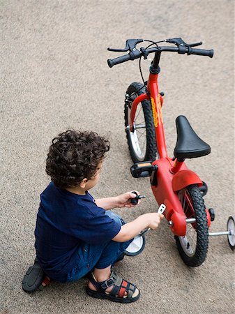 rodinha da bicicleta - boy fixing his bike Foto de stock - Royalty Free Premium, Número: 640-02777800