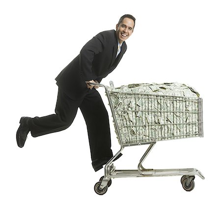 businessperson with a shopping cart full of money Stock Photo - Premium Royalty-Free, Code: 640-02778435