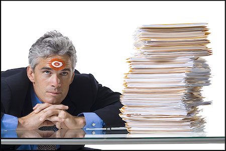 essere messo alle corde - Man with bull's-eye on forehead with stack of papers Fotografie stock - Premium Royalty-Free, Codice: 640-02770186