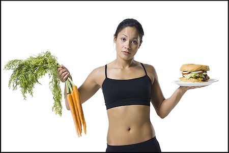 Woman choosing between carrots or hamburger Stock Photo - Premium Royalty-Free, Code: 640-02770314