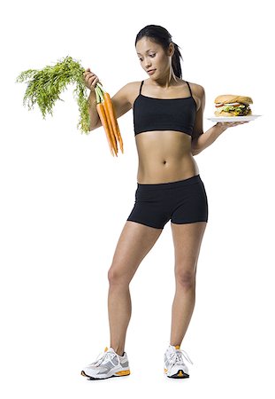 Woman choosing between carrots or hamburger Stock Photo - Premium Royalty-Free, Code: 640-02770316