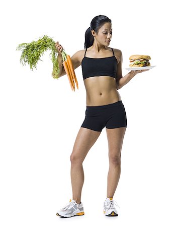 Woman choosing between carrots or hamburger Stock Photo - Premium Royalty-Free, Code: 640-02770317