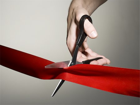 ribbon cutting scissors - Hand cutting a red ribbon with scissors Stock Photo - Premium Royalty-Free, Code: 640-02770533