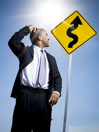 scratching head - Confused businessman in front of road sign Stock Photo - Premium Royalty-Free, Code: 640-02770558