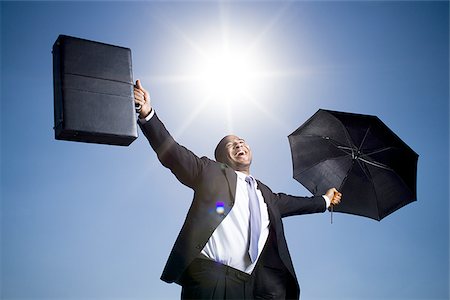 rain and sun - Businessman holding umbrella on a clear day Stock Photo - Premium Royalty-Free, Code: 640-02770568