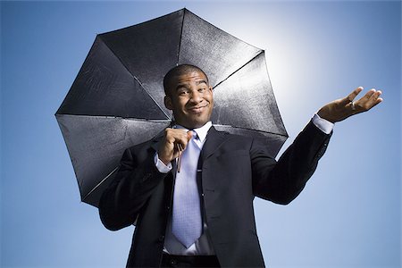 sun sky rain - Businessman holding umbrella on a clear day Stock Photo - Premium Royalty-Free, Code: 640-02770563