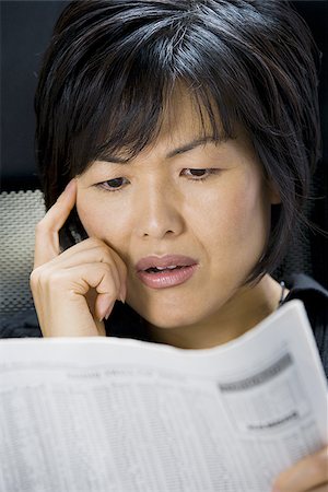 Woman reading financial pages of newspaper Stock Photo - Premium Royalty-Free, Code: 640-02770586