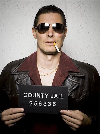 Mug shot of man with cigarette and sunglasses Foto de stock - Royalty Free Premium, Número: 640-02770813
