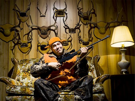 simsearch:640-01361763,k - Man on sofa with rifle and antlers Stock Photo - Premium Royalty-Free, Code: 640-02771066