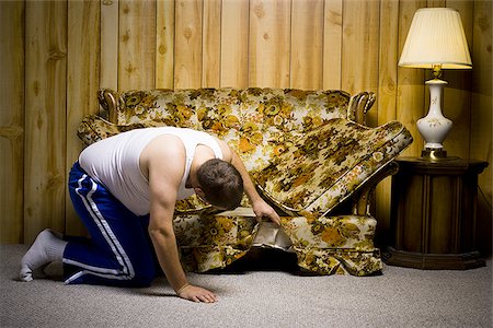 Man looking under sofa cushion Stock Photo - Premium Royalty-Free, Code: 640-02771070
