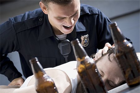simsearch:640-01351574,k - Police officer arresting man lying down with beer bottles Fotografie stock - Premium Royalty-Free, Codice: 640-02771216