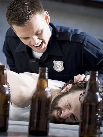 Police officer arresting man lying down with beer bottles Stock Photo - Premium Royalty-Free, Code: 640-02771217