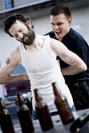 simsearch:640-01351574,k - Police officer arresting man lying down with beer bottles Fotografie stock - Premium Royalty-Free, Codice: 640-02771220