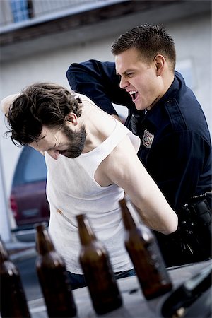 Agent de police arrêtant homme couché avec des bouteilles de bière Photographie de stock - Premium Libres de Droits, Code: 640-02771221