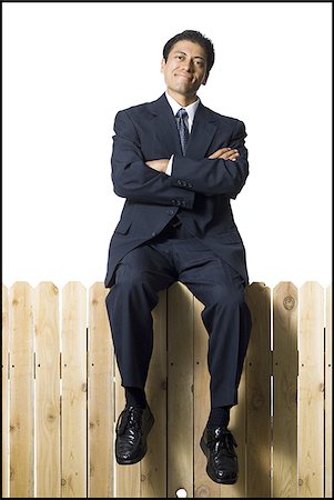 single man in arm of nature - Businessman sitting on fence smiling Stock Photo - Premium Royalty-Free, Code: 640-02771238