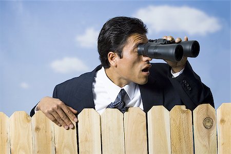 simsearch:640-02771261,k - Businessman looking through binoculars over wooden fence Stock Photo - Premium Royalty-Free, Code: 640-02771246