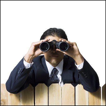 Businessman looking through binoculars over wooden fence Stock Photo - Premium Royalty-Free, Code: 640-02771247
