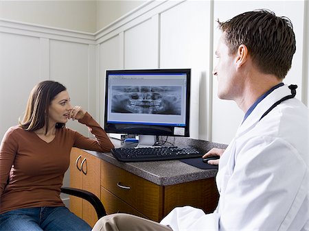 Male doctor or dentist looking at x-rays with woman Stock Photo - Premium Royalty-Free, Code: 640-02771542