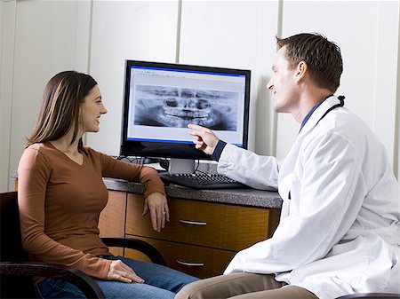 dental x rays - Male doctor or dentist looking at x-rays with woman Stock Photo - Premium Royalty-Free, Code: 640-02771543