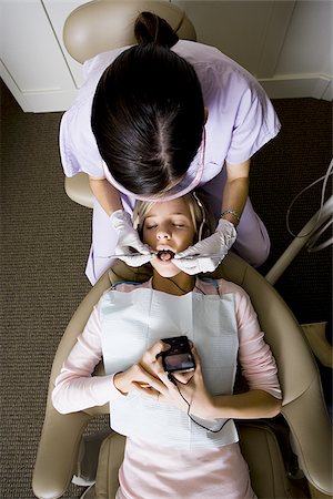 Girl having dental exam with mp3 player Stock Photo - Premium Royalty-Free, Code: 640-02771567