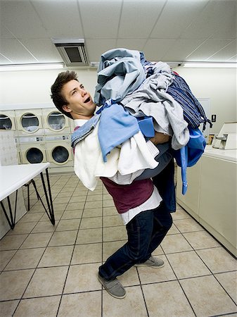 Man with pile of clothing in Laundromat Stock Photo - Premium Royalty-Free, Code: 640-02771622