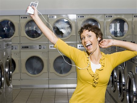 Woman with mp3 player in Laundromat dancing Stock Photo - Premium Royalty-Free, Code: 640-02771630