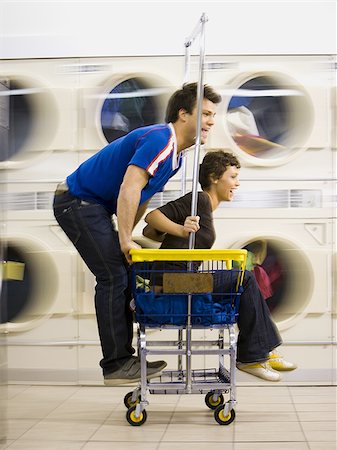 Young couple on trolley at Laundromat having fun Stock Photo - Premium Royalty-Free, Code: 640-02771654