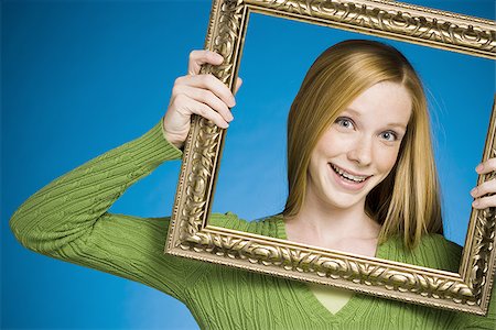 retainer - Girl looking through picture frame smiling Stock Photo - Premium Royalty-Free, Code: 640-02771904