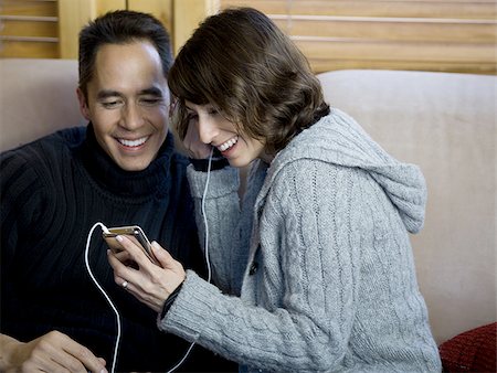 simsearch:640-02775245,k - Man and woman on sofa listening to music on mp3 player Stock Photo - Premium Royalty-Free, Code: 640-02771958