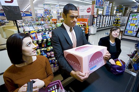 Man at grocery checkout with box of tampons and two women Stock Photo - Premium Royalty-Free, Code: 640-02772301