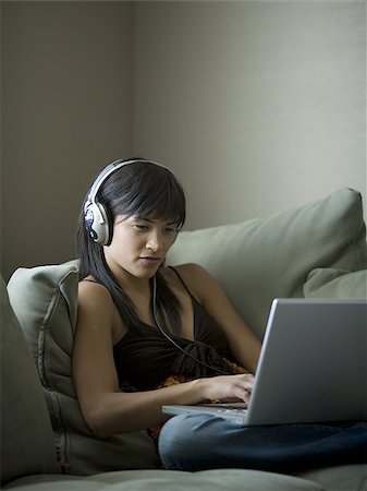 simsearch:640-02775245,k - Woman sitting on sofa with laptop and headphones Stock Photo - Premium Royalty-Free, Code: 640-02772782