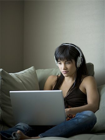 simsearch:640-02775245,k - Woman sitting on sofa with laptop and headphones Stock Photo - Premium Royalty-Free, Code: 640-02772783