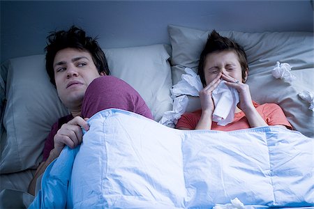 simsearch:640-01355958,k - Man laying in bed with woman blowing nose with tissue Stock Photo - Premium Royalty-Free, Code: 640-02772854