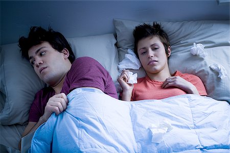 simsearch:640-01355958,k - Man laying in bed with woman blowing nose with tissue Stock Photo - Premium Royalty-Free, Code: 640-02772855