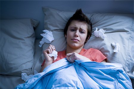 Woman lying in bed with tissues Stock Photo - Premium Royalty-Free, Code: 640-02772850