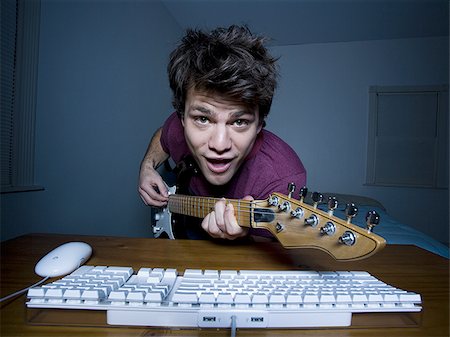Man at keyboard playing guitar and singing Stock Photo - Premium Royalty-Free, Code: 640-02772868