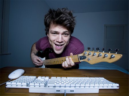 Man at keyboard playing guitar and singing Stock Photo - Premium Royalty-Free, Code: 640-02772869