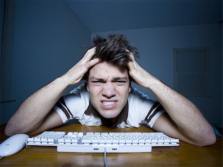 Man at keyboard with hands on head snarling Foto de stock - Sin royalties Premium, Código: 640-02772861